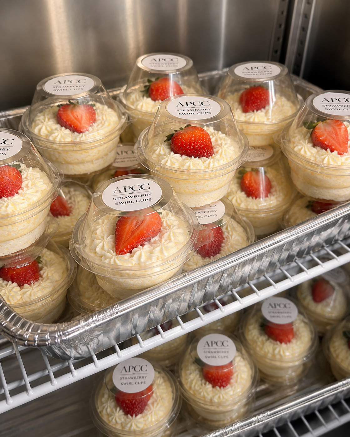 Tray of APCC swirl cups with branded lids, each topped with our signature strawberry